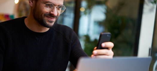 Cheerful ethnic man browsing smartphone