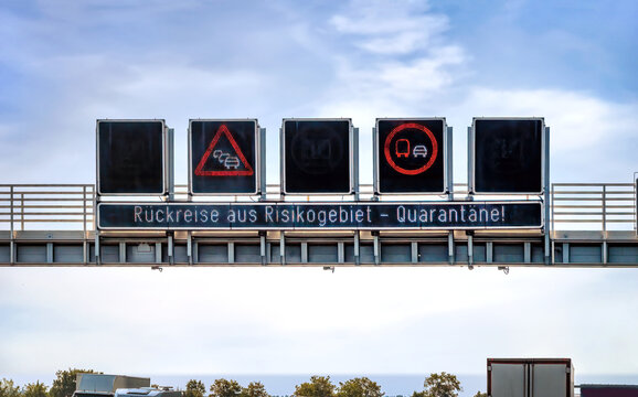 Schilderbrücke über der Autobahn, dass Urlauber sich nach der Heimkehr aus Risikogebieten in Quarantäne begeben sollen.