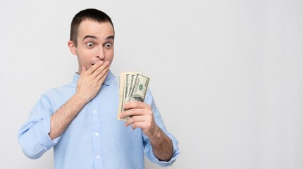 Concept of microloans. Stunned man with the cash dollars, white background, copy space