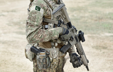 Soldier with machine gun and flag of Pakistan on military uniform. Collage.