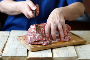 Selective focus. The chef cuts raw meat on the board. Cooking meat. Fresh pork for the grill.