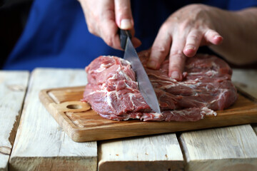 Selective focus. The chef cuts raw meat on the board. Cooking meat. Fresh pork for the grill.