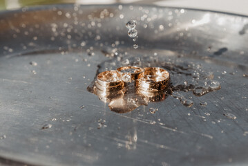wedding rings on a chrome plated surface. water drops with reflections of light. water splashes