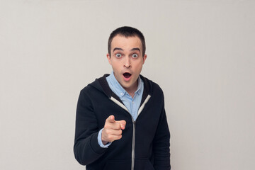 Stunned funny guy with open mouth pointing at the camera at you, copy space, white background