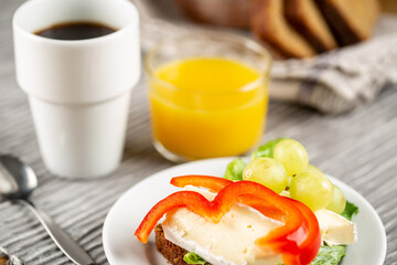 Hotel breakfast with coffee, sandwich with brie and grape and orange juice
