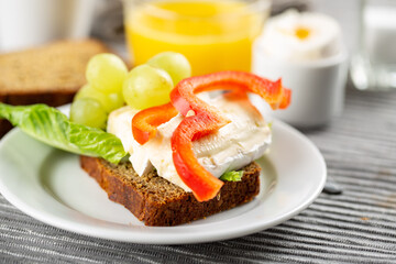 Hotel breakfast with sandwich with brie and grape, boiled egg and orange juice