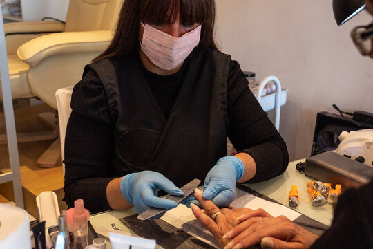 Beautiful women manicurist working with her client with mask.