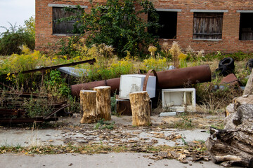 Felled trees against the background of an unfinished red brick house, an abandoned plot with a bunch of all sorts of things.