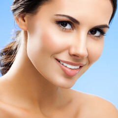 Obraz premium Portrait image of beautiful smiling young woman with naked shoulders, isolated over blue background