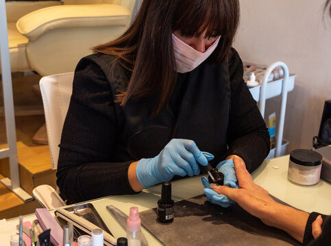 Beautiful women manicurist working with her client with mask.