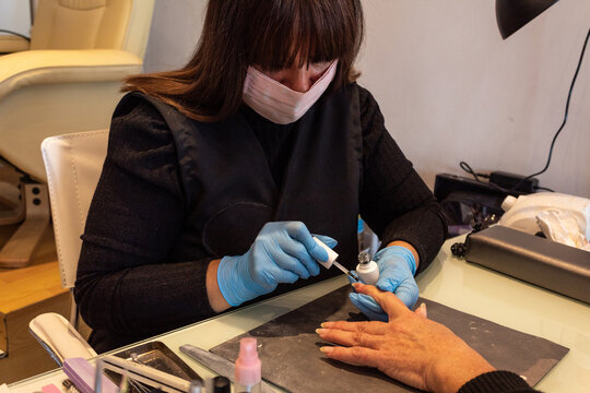 Beautiful women manicurist working with her client with mask.
