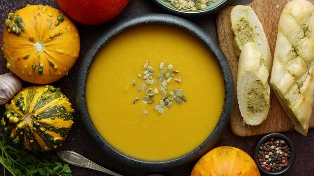 Homemade vegetarian pumpkin cream soup served in ceramic bowl. Decorated with seeds