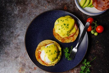 Homemade  Egg Benedict with perfect poached eggs Canadian bacon topped with Hollandaise sauce, selective focus