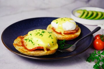 Homemade  Egg Benedict with perfect poached eggs Canadian bacon topped with Hollandaise sauce, selective focus