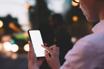 Anonymous person using smartphone with blank screen at evening