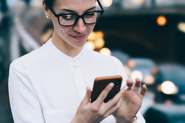 Smiling woman browsing smartphone in city