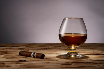 A glass of alcohol. Brandy on a beautiful table. Cognac and cigar on the background.