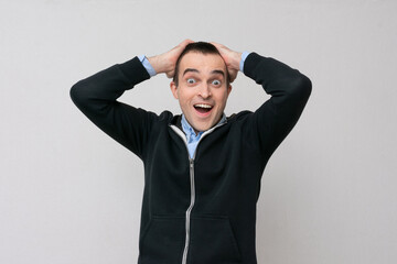 Excited man clutched his head in delight, white background, copy space
