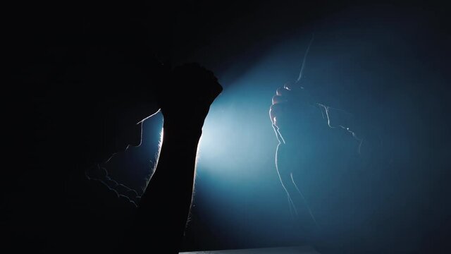 Silhouettes of men and women praying in the dark, the spotlight shines from behind