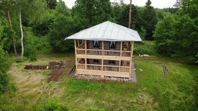 man works with a saw. renovates the house. two-storey wooden house hill forest