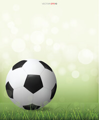 Fototapeta premium Soccer football ball on green grass field with light blurred bokeh background. Vector.