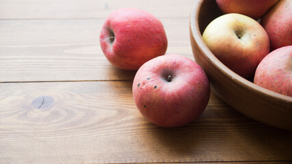 Fresh red apples with green leaves on wooden table.