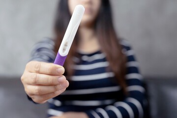 A woman carrying a pregnancy test with birth control pills