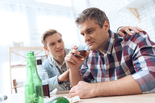 Father Drinks Alcoholic While Son Sits Nearby.