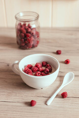 Fresh homemade oatmeal with raspberries in bowl on the table in the kitchen. Delicious breakfast