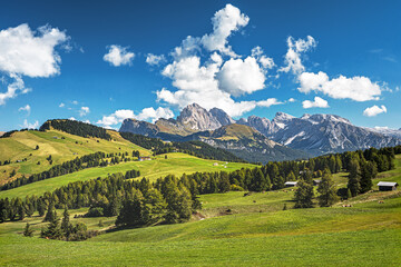 Famous Alpe di Siusi - Seiser Alm with Sassolungo - Langkofel mountain group in background at sunset. Wooden chalets in Dolomites, Trentino Alto Adige region, South Tyrol, Italy