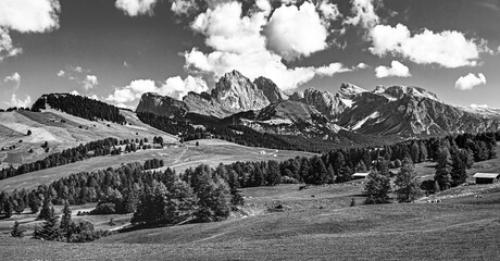 Fototapeta premium Famous Alpe di Siusi - Seiser Alm with Sassolungo - Langkofel mountain group in background at sunset. Wooden chalets in Dolomites, Trentino Alto Adige region, South Tyrol, Italy