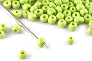 Beads spread on white background with needle. Beads with needle . Close up, macro,It is used in finishing fashion clothes. make bead necklace, beads for woman of fashion,Bead Crochet. Daily Beading.