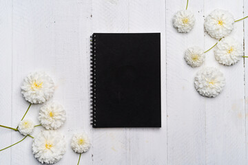 Obraz premium Notebooks and flowers-The book and white flowers on the white wooden table