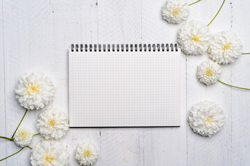 Obraz premium Notebooks and flowers-The book and white flowers on the white wooden table