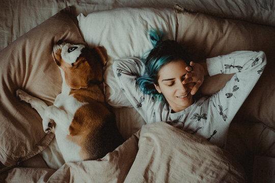 High Angle View Of Woman With Dog Sleeping On Bed At Home