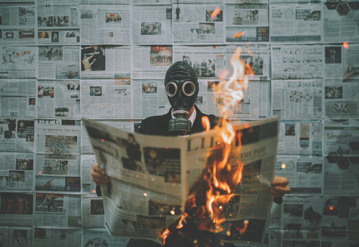 Man Holding Burning Paper While Wearing Gas Mask Against Wall
