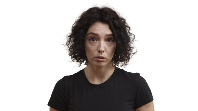 Close-up of young attractive woman with short curly hair, wearing black t-shirt, saying no to someone, forbid action with serious face, rejecting or denying offer, white background