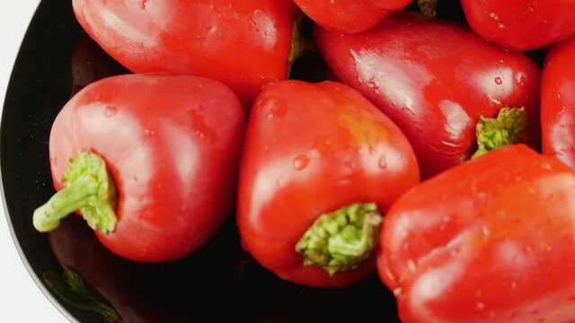 Red pepper on a black plate.Bell peppers whole with a green twig.