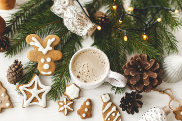 Obraz na płótnie Canvas Christmas gingerbread cookies, coffee in stylish cup, pine cones white wooden table, top view