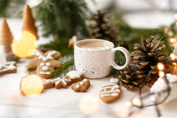 Christmas gingerbread cookies, coffee, pine cones  and warm lights on white wooden table