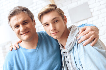 Dad and son hug each other and look at the camera.
