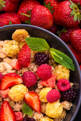 Mueslis with berries in a black white cup on the table, macro