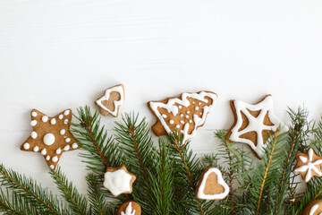 Christmas gingerbread cookies and fir branches border on white wooden background