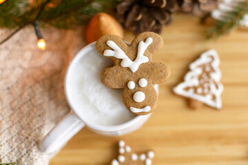Christmas reindeer gingerbread cookie on aromatic coffee on background of cozy knitted sweater