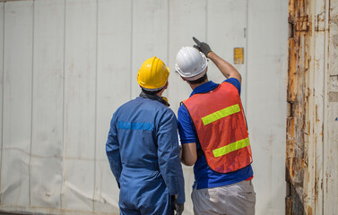 A male engineer and a worker standing in control of the container inspection, exporting goods abroad at the port
