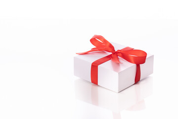 White square cardboard gift box tied with red satin ribbon and bow isolated on white background copy space close up. surprise in holiday festive. st valentines day gift
