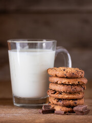 Chocolate chips cookies with crumbs and fresh milk on wooden background, homemade sweet and dessert concept