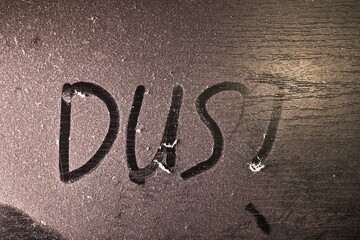 Thick layer of dust on a shelf with word dust written in it