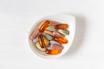 Variety of vitamin pills on white wooden background, supplemental and healthcare product, flat lay surface
