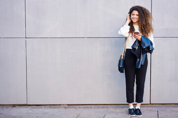 Cheerful woman browsing smartphone on street